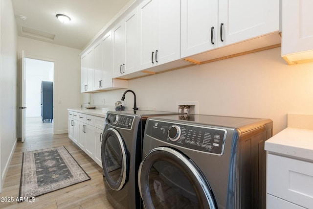 washroom featuring cabinets, light wood-type flooring, and washer and clothes dryer