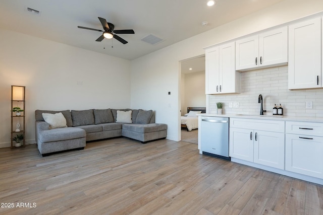 kitchen featuring tasteful backsplash, dishwasher, sink, and white cabinets