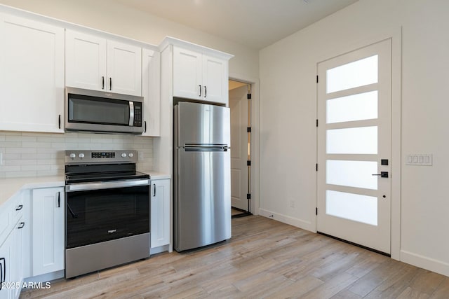 kitchen featuring decorative backsplash, light hardwood / wood-style flooring, white cabinets, and appliances with stainless steel finishes