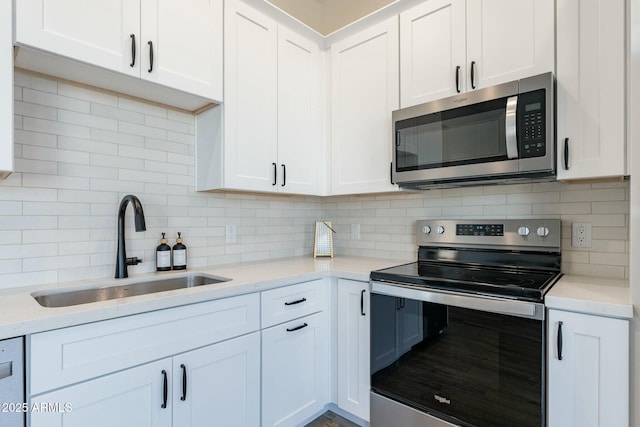 kitchen featuring sink, appliances with stainless steel finishes, white cabinetry, tasteful backsplash, and light stone countertops