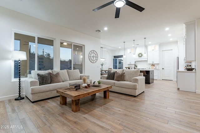 living room with ceiling fan, sink, and light hardwood / wood-style floors