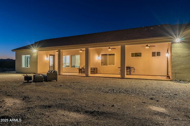 back house at dusk featuring ceiling fan and a patio area