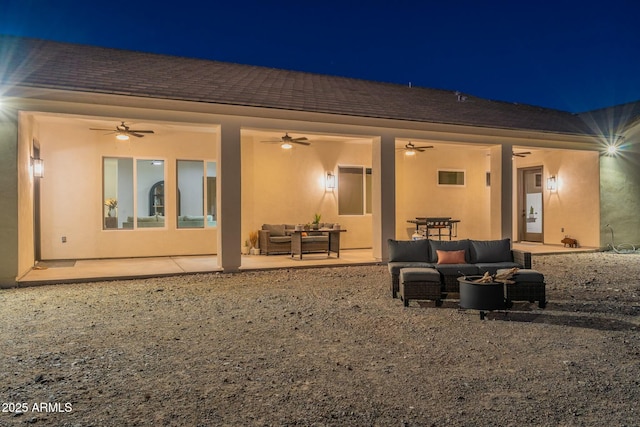 back house at night featuring an outdoor living space, a patio, and ceiling fan