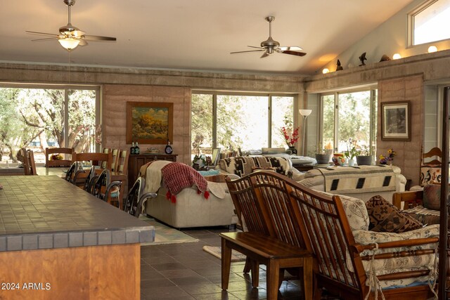 living room featuring dark tile patterned floors, a ceiling fan, and lofted ceiling