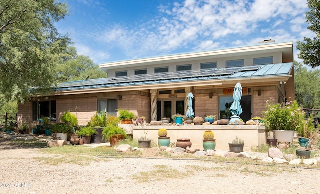 back of property with solar panels, metal roof, and a standing seam roof