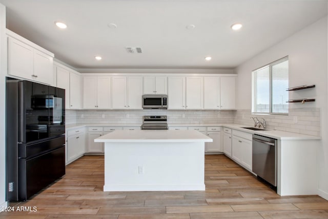 kitchen featuring white cabinetry, stainless steel appliances, tasteful backsplash, and a center island