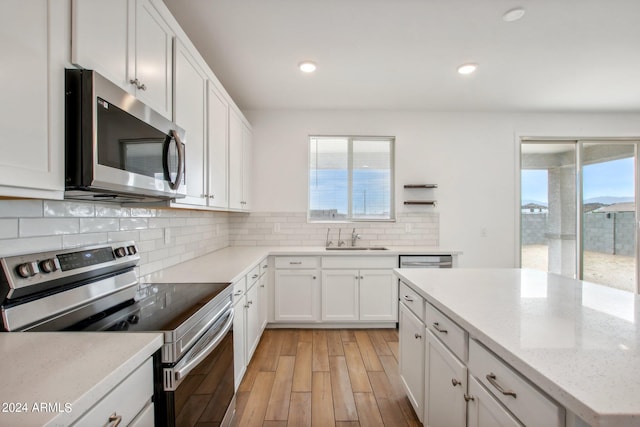 kitchen with light hardwood / wood-style floors, appliances with stainless steel finishes, a healthy amount of sunlight, and backsplash