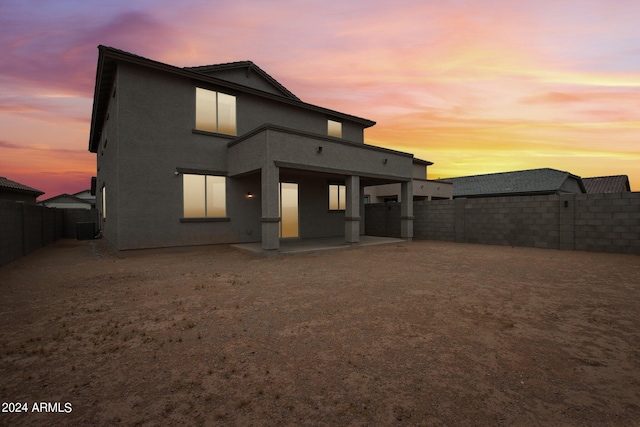 back house at dusk featuring a patio