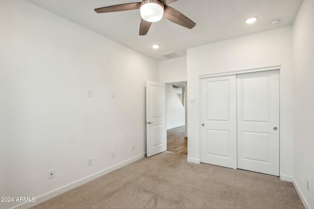 unfurnished bedroom with light carpet, ceiling fan, and a closet