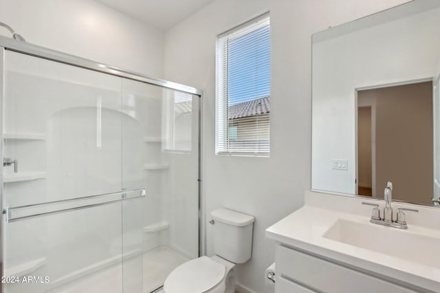 bathroom featuring a shower with door, vanity, and toilet