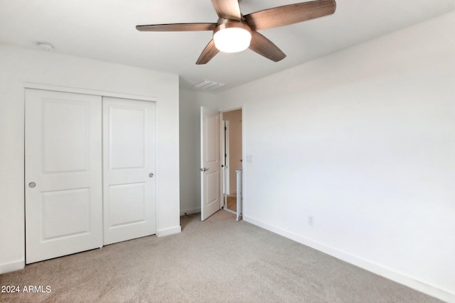 unfurnished bedroom featuring light carpet, a closet, and ceiling fan