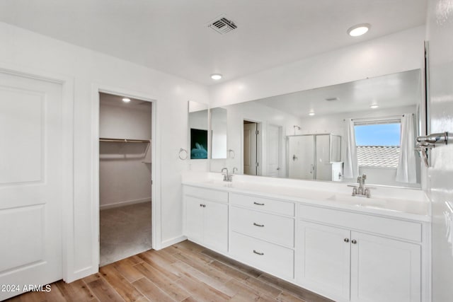 bathroom featuring hardwood / wood-style floors, an enclosed shower, and dual bowl vanity