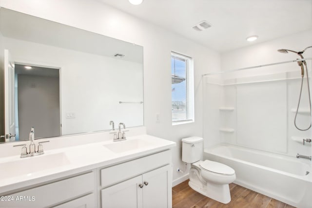 full bathroom with dual vanity, shower / bath combination, wood-type flooring, and toilet