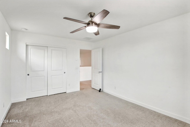 unfurnished bedroom featuring ceiling fan, light carpet, and a closet