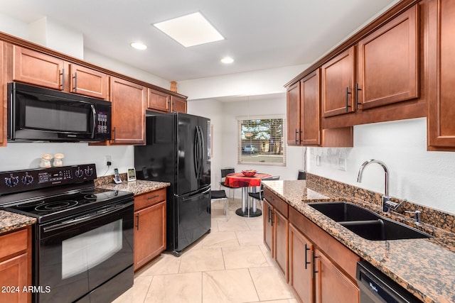 kitchen featuring sink, dark stone counters, and black appliances