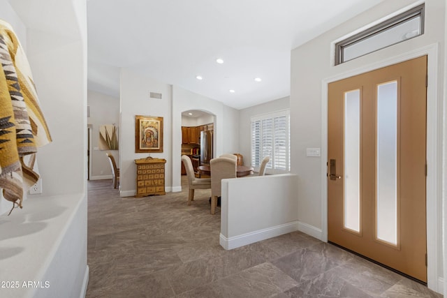 foyer entrance featuring arched walkways, visible vents, baseboards, and recessed lighting