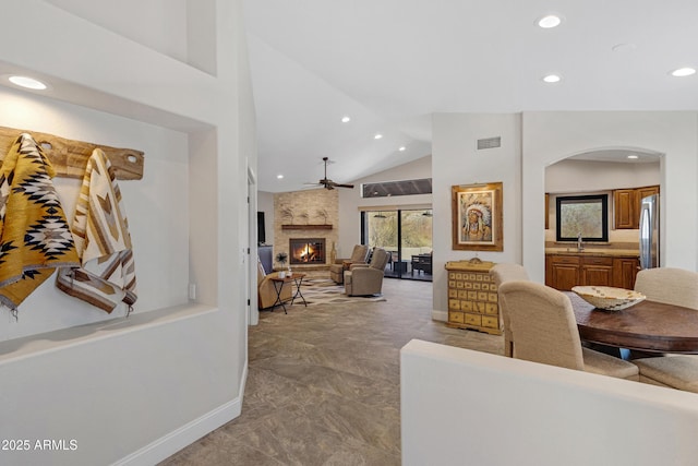 living room featuring arched walkways, recessed lighting, visible vents, a stone fireplace, and baseboards