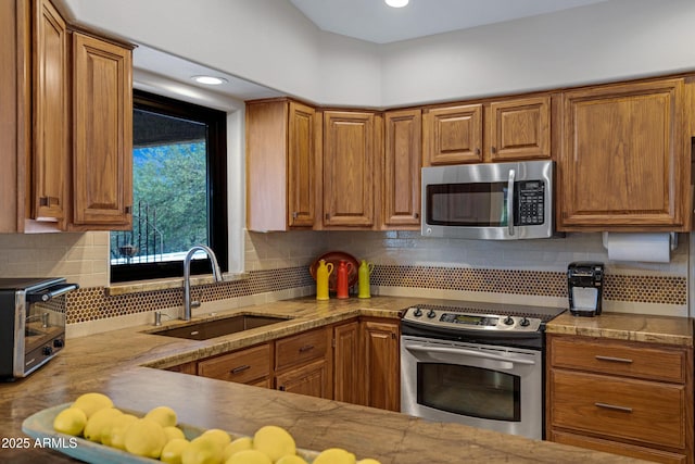 kitchen featuring a toaster, brown cabinets, a sink, stainless steel appliances, and backsplash