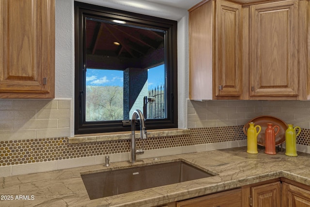 kitchen with tasteful backsplash, brown cabinets, and a sink