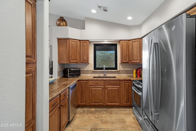 kitchen with light stone countertops, a sink, visible vents, appliances with stainless steel finishes, and brown cabinets