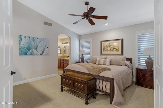 bedroom with arched walkways, lofted ceiling, visible vents, light carpet, and baseboards