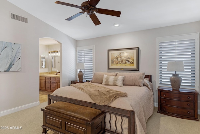 bedroom with arched walkways, visible vents, light carpet, vaulted ceiling, and baseboards