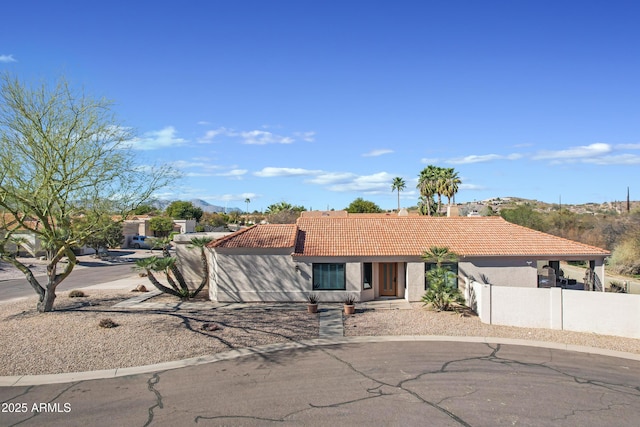 view of front of home with stucco siding, a tile roof, and fence