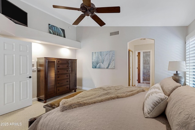 bedroom with light carpet, visible vents, arched walkways, baseboards, and ceiling fan