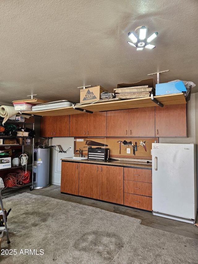 garage featuring electric water heater, a workshop area, a sink, and freestanding refrigerator