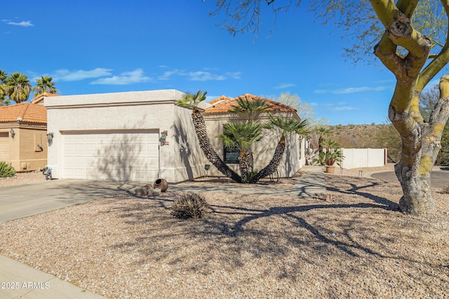 view of front of house featuring driveway, a tile roof, an attached garage, fence, and stucco siding