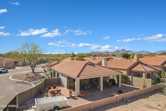 exterior space featuring a patio, a fenced backyard, a mountain view, a tile roof, and a residential view