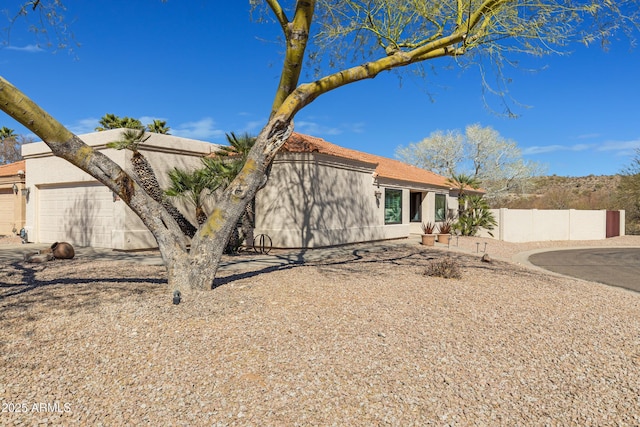 view of front of home with fence, an attached garage, and stucco siding