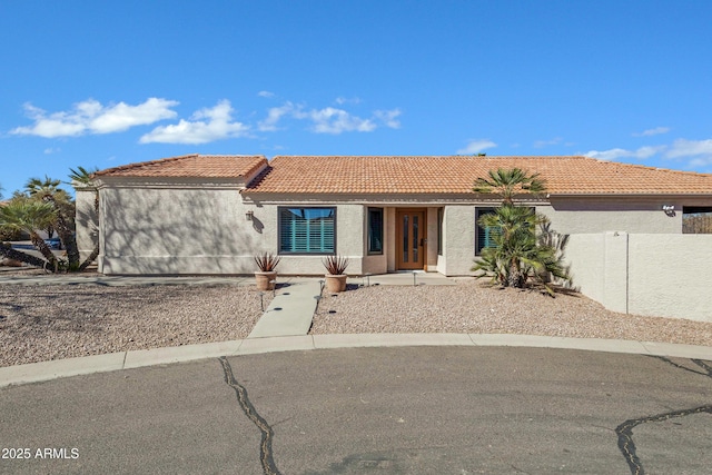 view of front of home with a tile roof, fence, and stucco siding