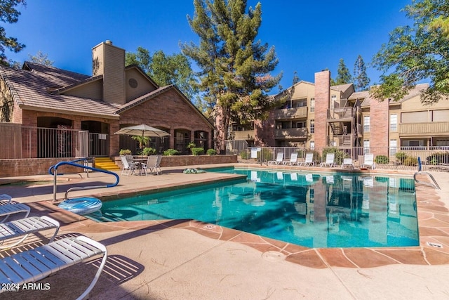 view of swimming pool featuring fence and a patio