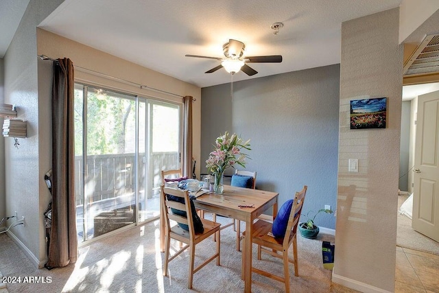 dining room featuring light tile patterned floors, ceiling fan, baseboards, and a textured wall