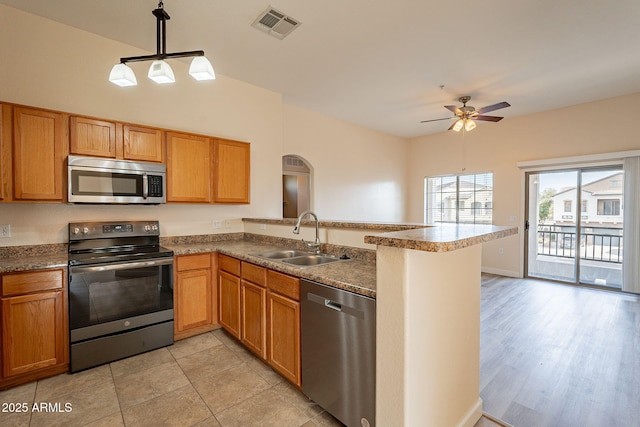 kitchen with visible vents, appliances with stainless steel finishes, a peninsula, pendant lighting, and a sink