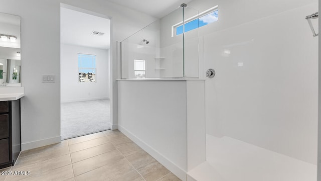full bathroom featuring walk in shower, vanity, baseboards, and tile patterned flooring