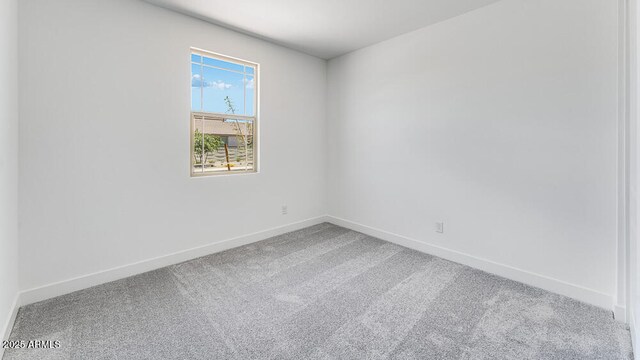 carpeted spare room featuring baseboards