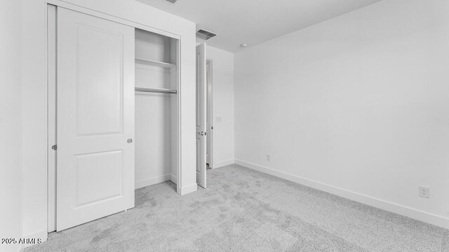 unfurnished bedroom with carpet, a closet, and baseboards