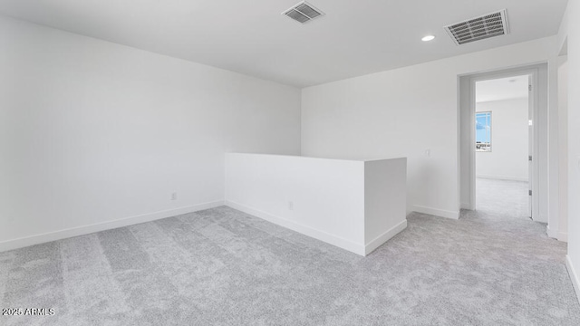 empty room with light colored carpet, recessed lighting, and baseboards