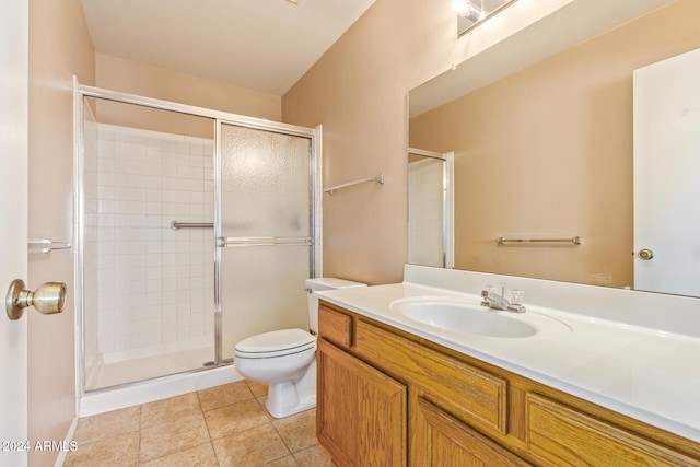 bathroom with tile patterned flooring, vanity, toilet, and a shower with shower door