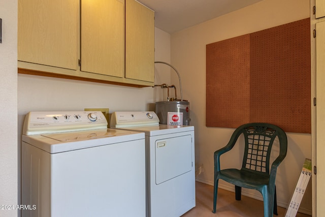 washroom featuring washing machine and clothes dryer, cabinets, and water heater