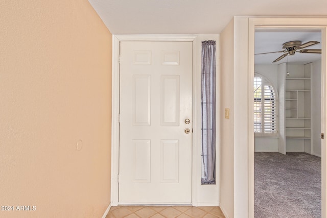 entryway with ceiling fan and light colored carpet