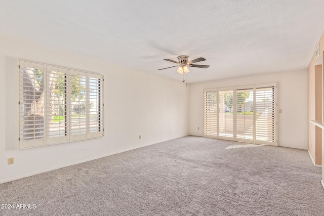 carpeted empty room featuring a textured ceiling, ceiling fan, and a healthy amount of sunlight