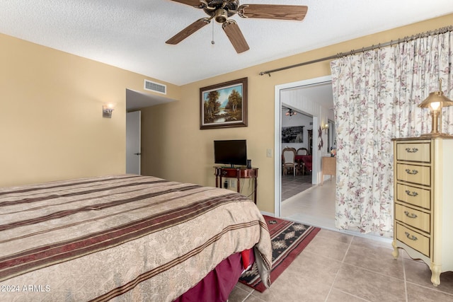 tiled bedroom featuring ceiling fan, a textured ceiling, and a closet