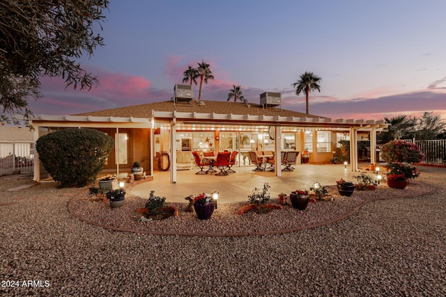 back house at dusk featuring a patio area