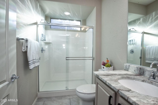 bathroom featuring tile patterned flooring, toilet, vanity, and walk in shower