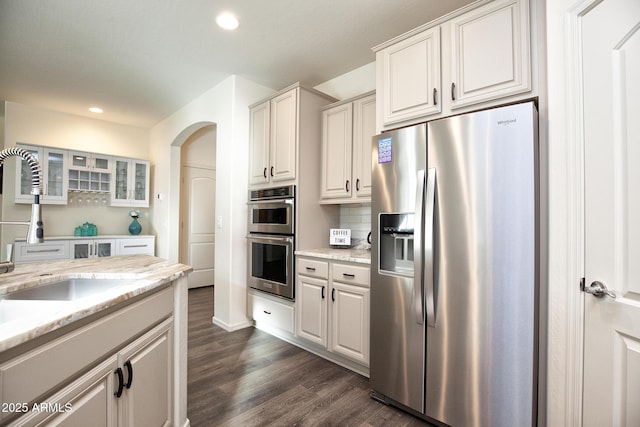 kitchen featuring sink, appliances with stainless steel finishes, dark hardwood / wood-style floors, white cabinets, and decorative backsplash