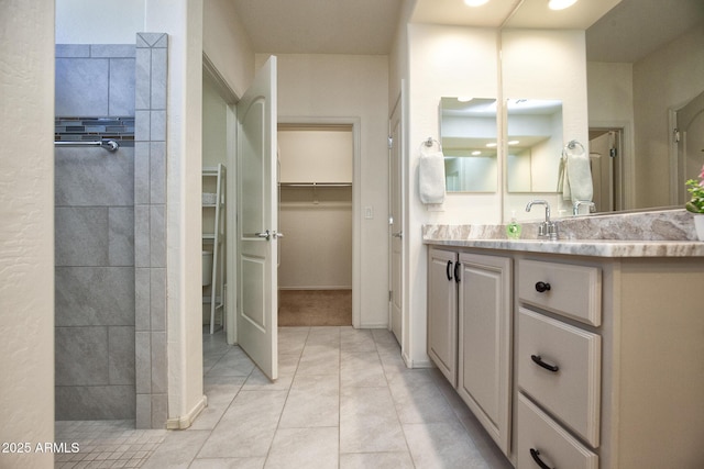 bathroom featuring vanity, tile patterned floors, and tiled shower