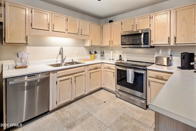 kitchen with light brown cabinets, light tile patterned flooring, sink, and appliances with stainless steel finishes